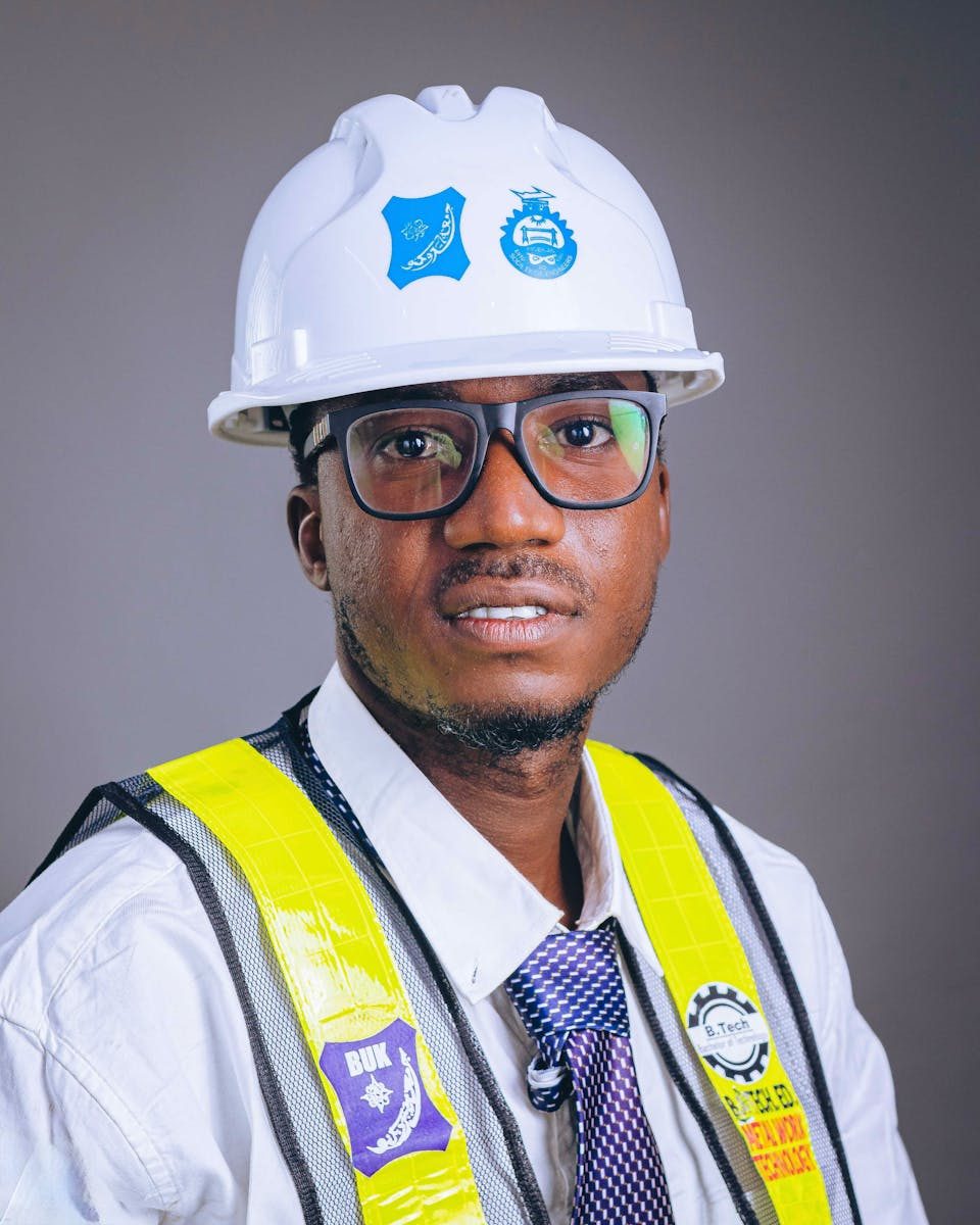 Professional African engineer wearing safety gear and helmet, posing confidently in studio.