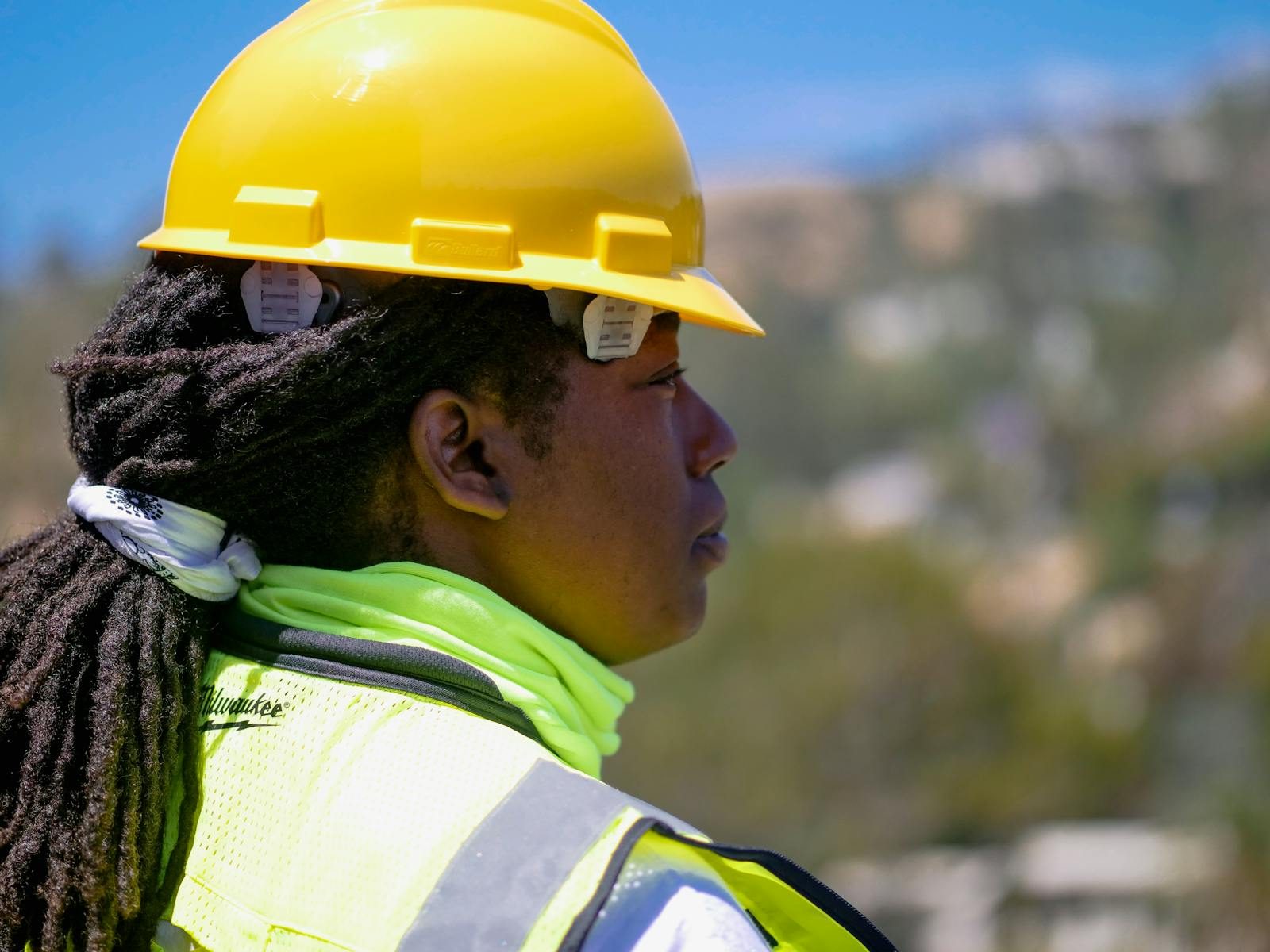 Professional female engineer wearing safety gear and hardhat at a construction site outdoors.